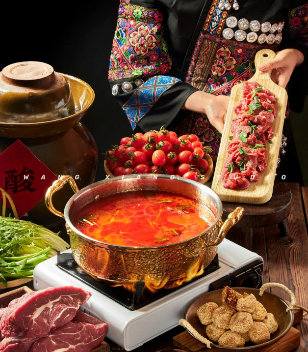 A steaming pot of Guizhou-style sour soup showing bright red broth with chilies, tomatoes, and aromatic ingredients, highlighting the traditional sour and spicy flavor profile