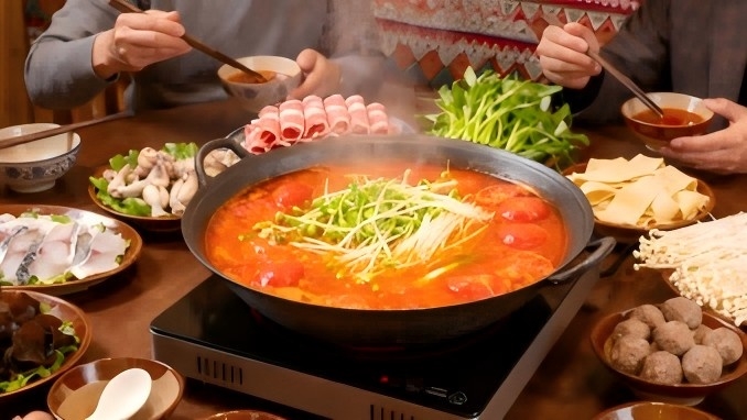 Authentic Kaili sour soup from Guizhou, China — bright red fermented broth with tomatoes, dried chili peppers, and herbs in a rustic ceramic bowl.